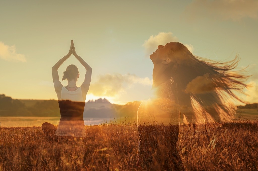 Carefree beautiful happy woman meditating grass meadow enjoying sun on her face. Enjoying nature freedom at sunrise in nature. Mind body spirit health concept.